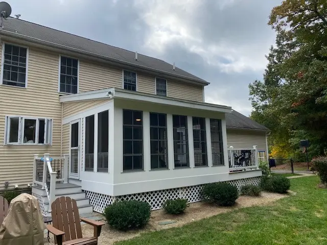 New screened porch and deck addition on the back of an existing home with landscaping