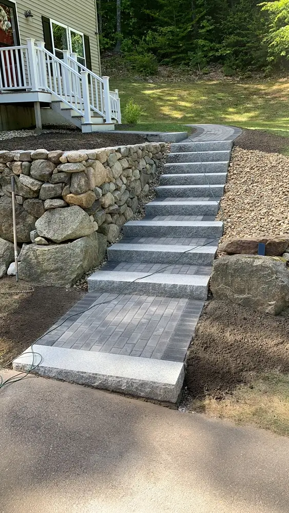 New granite and stone walkway and steps with brick retaining wall leading up to exterior entry of home