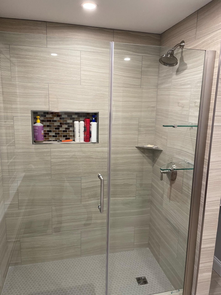 Remodeled tile shower with glass door and built in storage