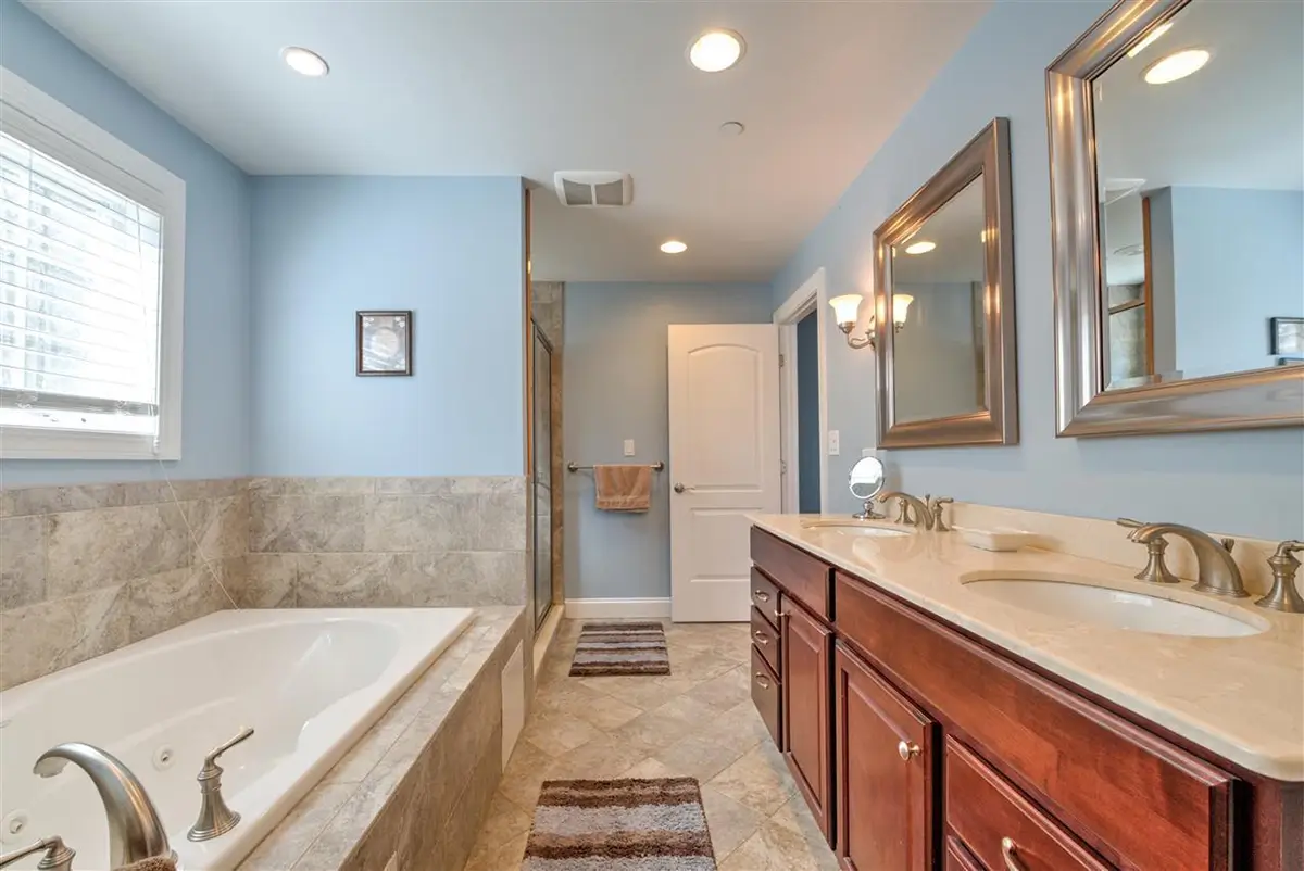 Beautifully remodeled master bathroom with dual sink vanity and tile soaking tub