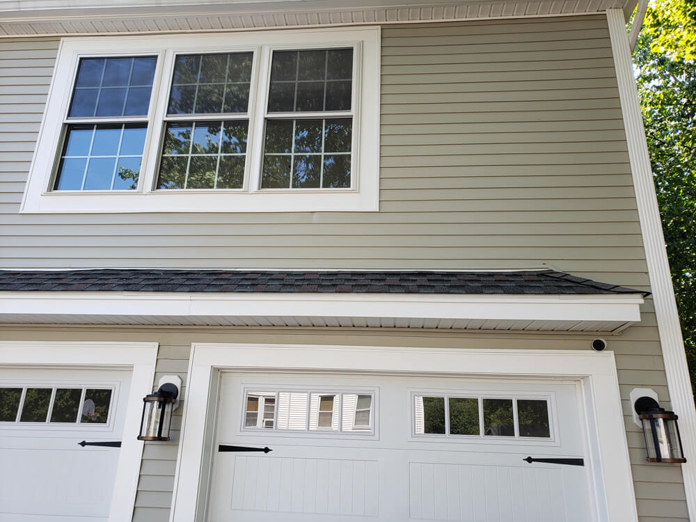 New home addition, garage and bonus room exterior shot house with two white garage doors