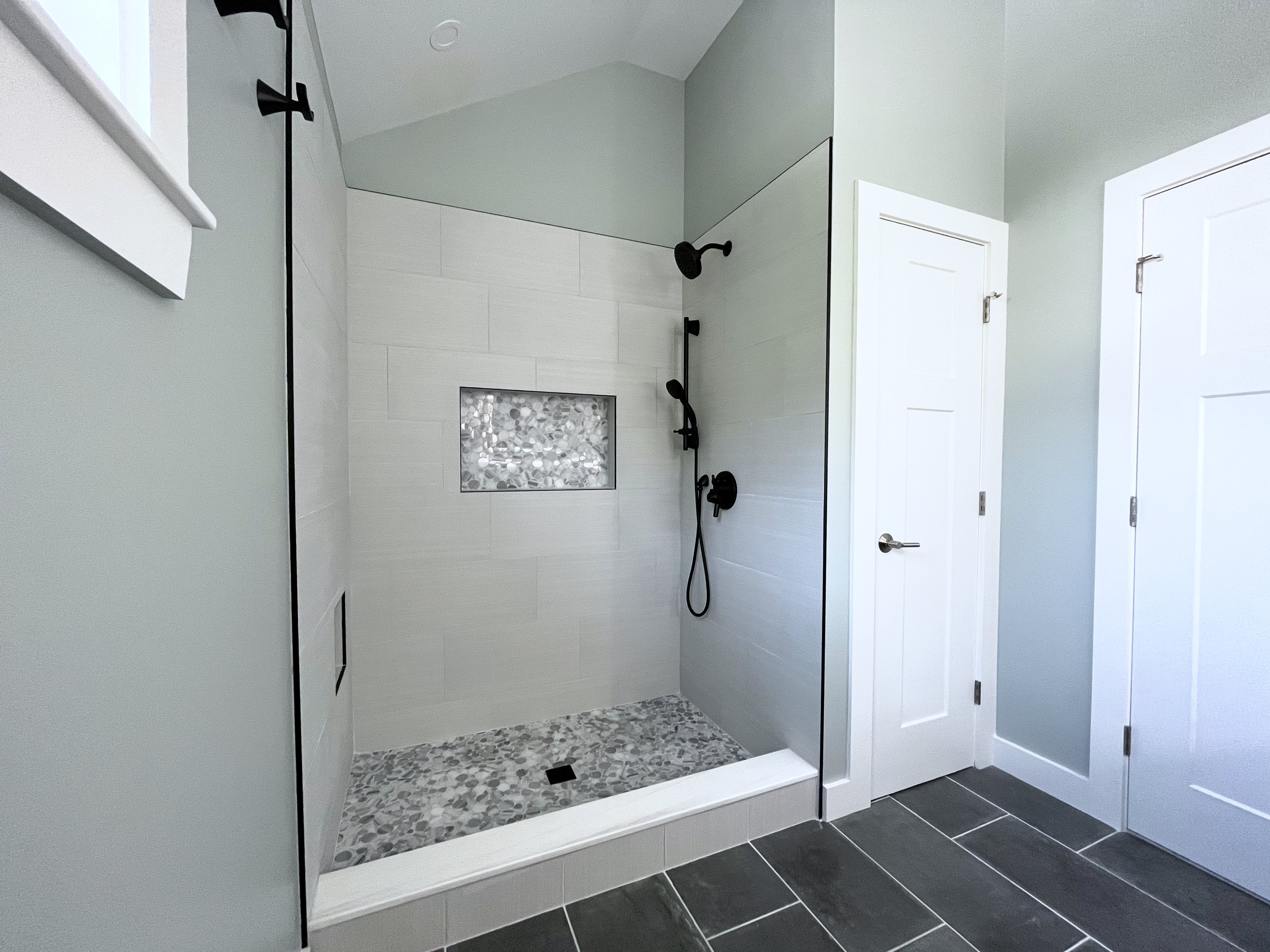 Master bathroom shower with new white tiles, granite step and matte black fixtures