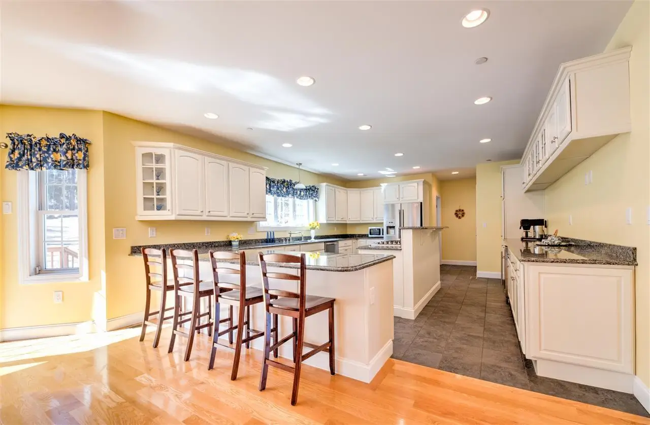 Newly remodeled kitchen with hardwood and tile floors, modern white cabinets, granite, countertops, and kitchen island with range