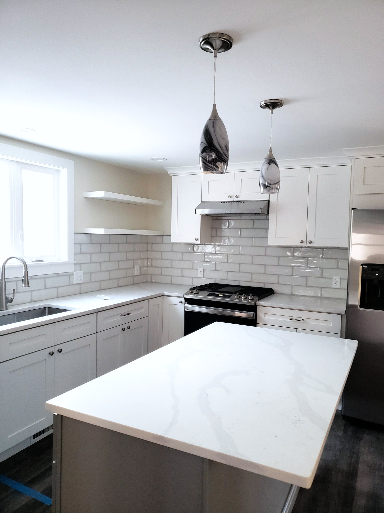 White kitchen cabinets with new granite island and backsplash