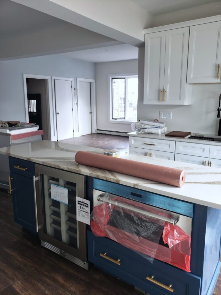 Kitchen Remodeling with beautiful granite countertops, white cabinets and navy blue island cabinet